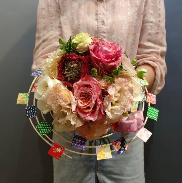 Intermediate floristry course, student holding a structure bouquet with roses, lisianthus and butterfly ranunculus