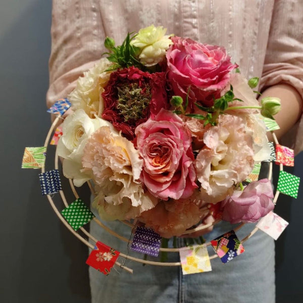 Intermediate floristry course, student holding a structure bouquet with roses, lisianthus and butterfly ranunculus