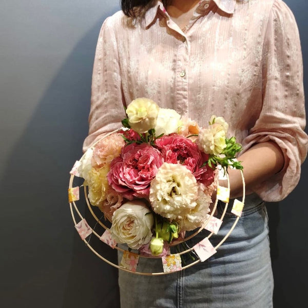 Intermediate floristry course, student holding a structure bouquet with roses, lisianthus and butterfly ranunculus