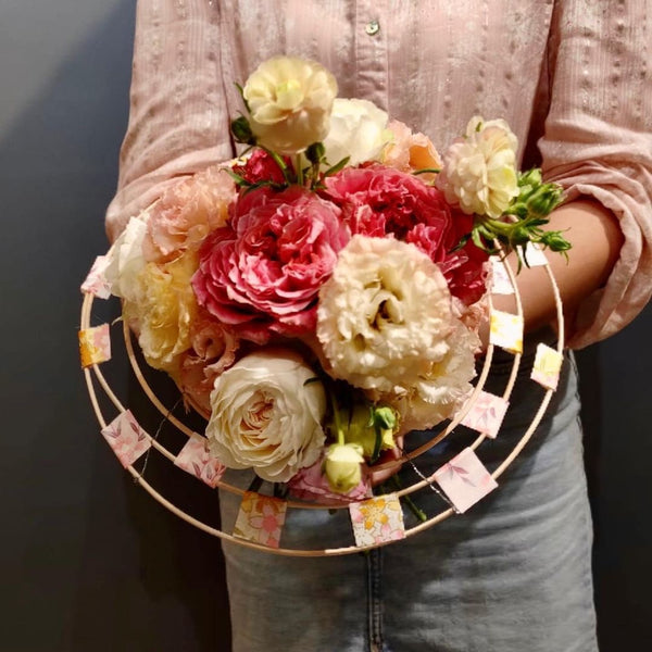 Intermediate floristry course, student holding a structure bouquet with roses, lisianthus and butterfly ranunculus