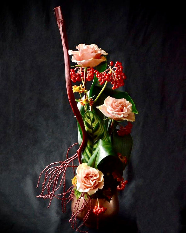 Intermediate floristry course, vertical flower arrangement with dried and painted alexander palm seeds, roses and viburnum berries, featuring leaf manipulation technique