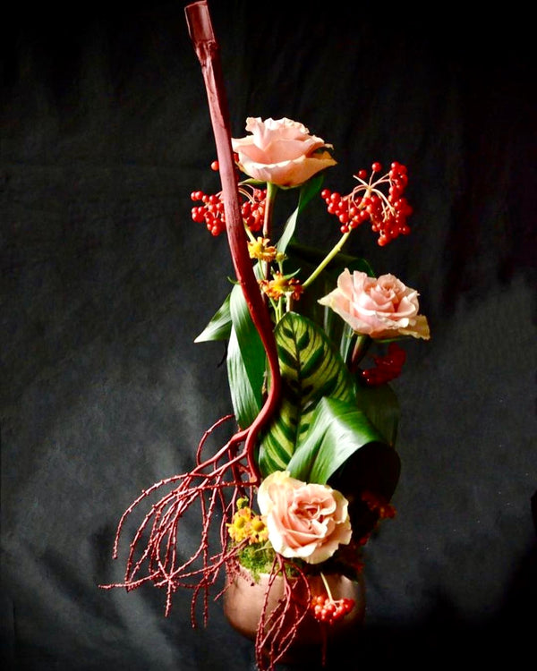 Intermediate floristry course, vertical flower arrangement with dried and painted alexander palm seeds, roses and viburnum berries, featuring leaf manipulation technique