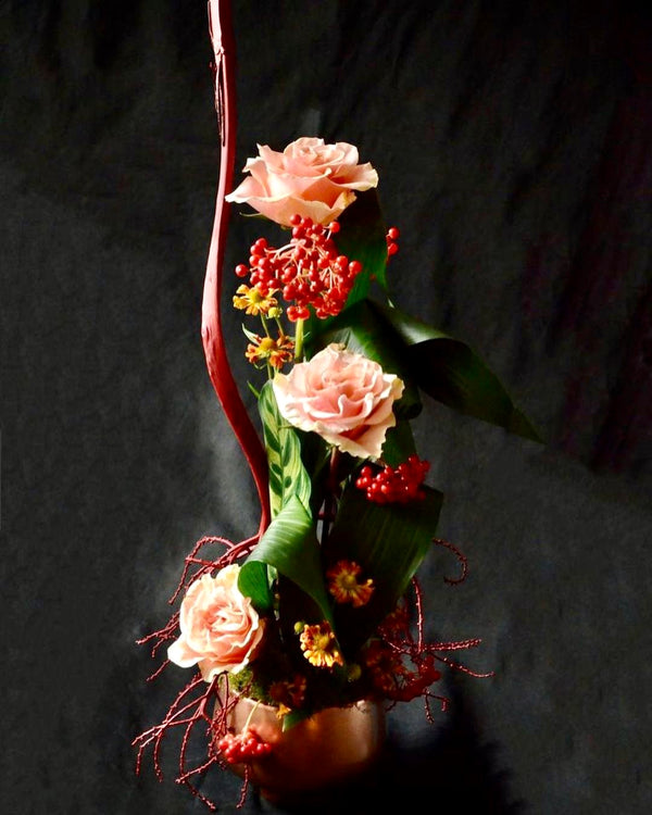 Intermediate floristry course, vertical flower arrangement with dried and painted alexander palm seeds, roses and viburnum berries, featuring leaf manipulation technique