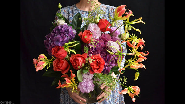 Hand-tied Bouquet Workshop, student holding a finished hand tied bouquet with hydrangeas, roses, lisianthus and gloriosa
