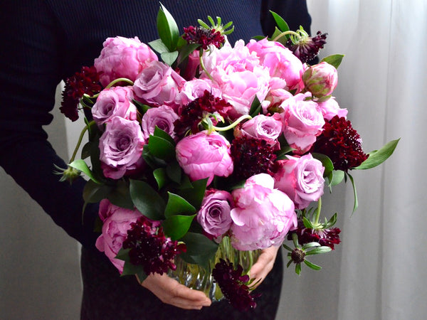 Hand-tied Bouquet Workshop, student holding a hand tied bouquet with peonies, roses and scabiosa