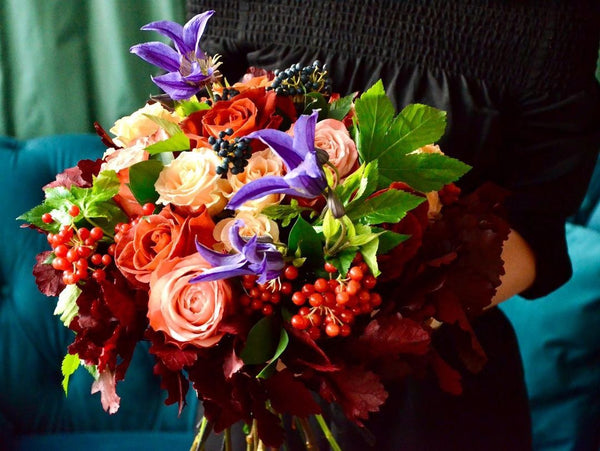 Floristry class. Student holding her work - hand-tied bouquet in autumn colours.
