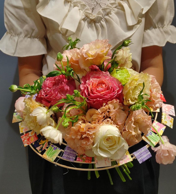 Intermediate floristry course, student holding a structure bouquet with roses, lisianthus and butterfly ranunculus