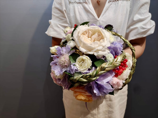Intermediate floristry course, student holding a bouquet in bouquet holder with hydrangeas, roses, viburnum berries and scabiosa, featuring bear grass braiding technique